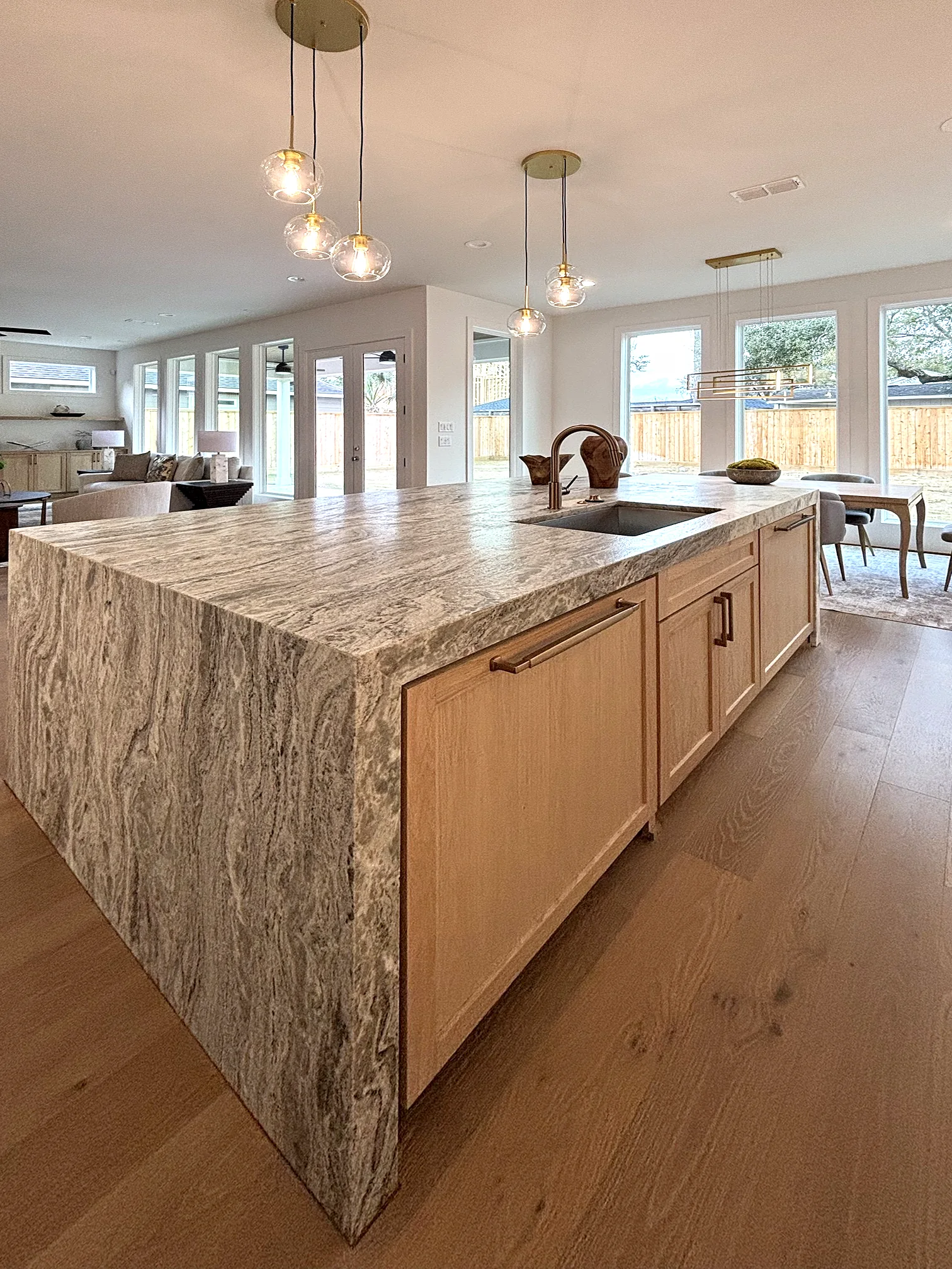 Kitchen island with pendant lighting beneath a wall of windows