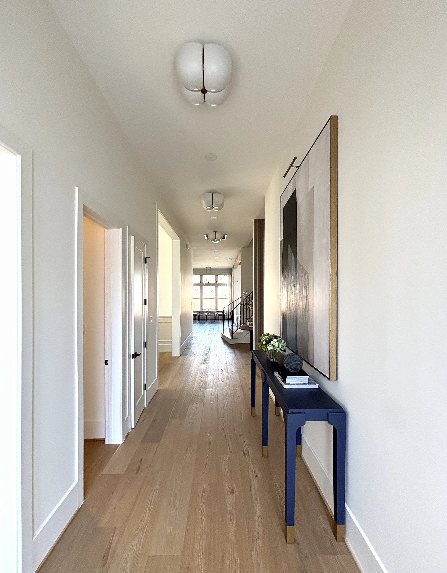 Hallway with wall sconces and a statement ceiling fixture
